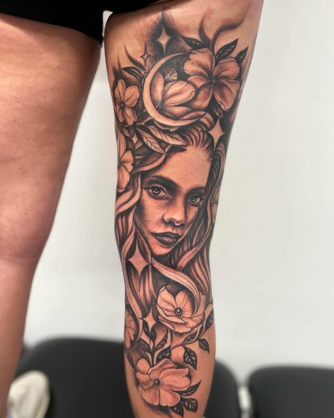 Tatuaje profesional en estudio MartinK Tattoo de un retrato realista con flores y una luna