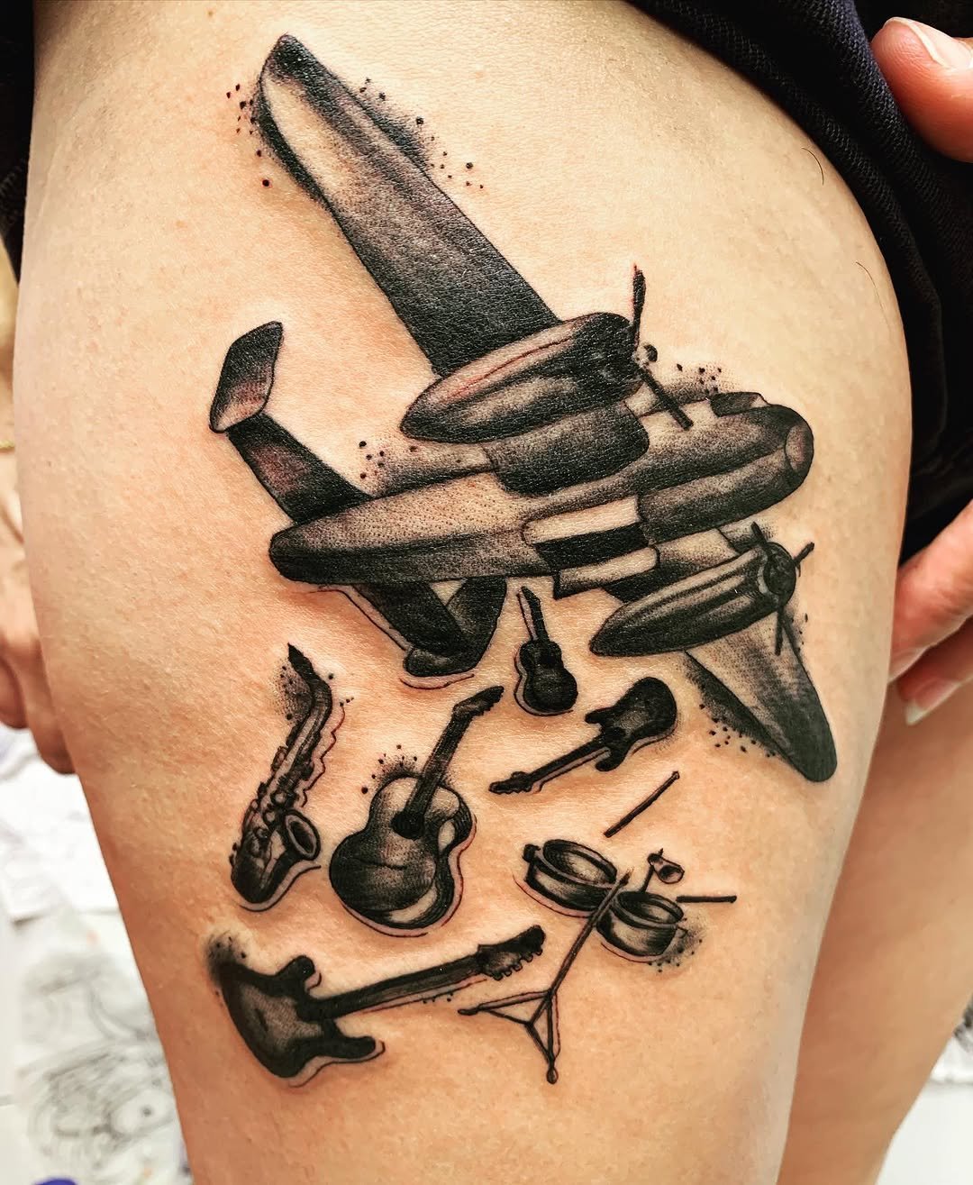 Tatuaje profesional en estudio MartinK Tattoo avión lanzando instrimentos musicales